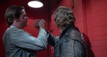 Movie still from “Phantom of the Paradise” (1974), directed by Brian De Palma – Two men arm wrestling each other in front of a red wall; Medium shot, Low angle