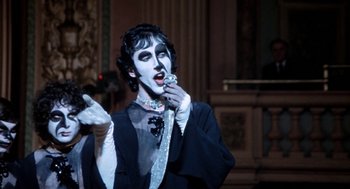 Movie still from “Phantom of the Paradise” (1974), directed by Brian De Palma – A man in a black and white costume and makeup; Medium shot, Over the shoulder angle