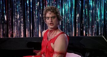 Movie still from “Phantom of the Paradise” (1974), directed by Brian De Palma – A man dressed in a red dress with red makeup; Medium shot, Low angle