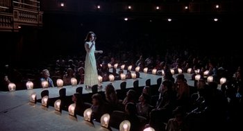 Movie still from “Phantom of the Paradise” (1974), directed by Brian De Palma – A woman standing on a runway in front of a crowd; Wide shot, High angle