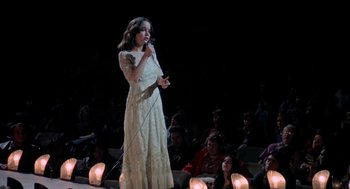 Movie still from “Phantom of the Paradise” (1974), directed by Brian De Palma – A woman in a long white dress holding a microphone; Medium shot, High angle