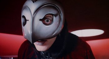 Movie still from “Phantom of the Paradise” (1974), directed by Brian De Palma – A person wearing a mask with an owl face; Close Up shot, Low angle