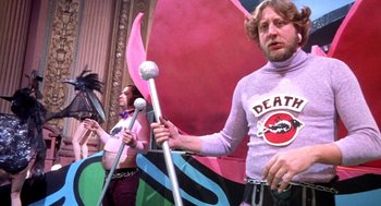 Movie still from “Phantom of the Paradise” (1974), directed by Brian De Palma – A group of people standing next to each other holding microphones; Medium shot, Low angle