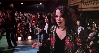 Movie still from “Phantom of the Paradise” (1974), directed by Brian De Palma – A group of people in a room with a crowd of onlookers; Medium shot, High angle