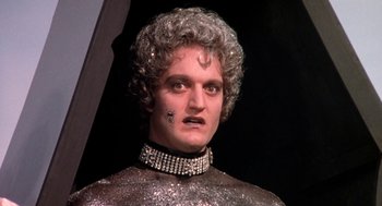 Movie still from “Phantom of the Paradise” (1974), directed by Brian De Palma – A man in a silver outfit and a silver necklace; Close Up shot, Low angle