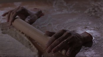 Movie still from “Phantoms” (1998), directed by Joe Chappelle – A person holding a baseball bat on top of a table; Extreme Close Up shot, High angle