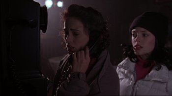 Movie still from “Phantoms” (1998), directed by Joe Chappelle – A woman holding a cell phone up to her ear while standing next to another woman; Close Up shot, High angle