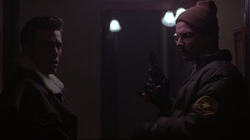Movie still from “Phantoms” (1998), directed by Joe Chappelle – A man holding a gun in front of another man; Close Up shot, Over the shoulder angle