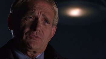 Movie still from “Phantoms” (1998), directed by Joe Chappelle – An older man in a suit and tie looking at the camera; Close Up shot, Low angle