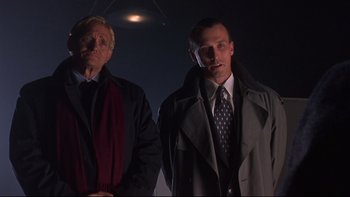 Movie still from “Phantoms” (1998), directed by Joe Chappelle – Two men standing next to each other in a dark room; Medium shot, Low angle