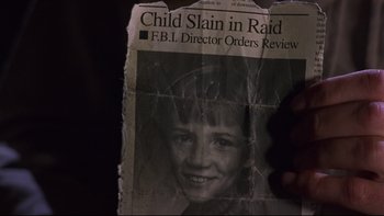 Movie still from “Phantoms” (1998), directed by Joe Chappelle – A newspaper with a picture of a boy in a black and white photo; Extreme Close Up shot, Overhead angle