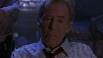 Movie still from “Phantoms” (1998), directed by Joe Chappelle – An older man wearing a neck tie in a dark room; Close Up shot, Low angle
