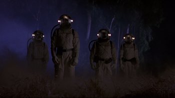 Movie still from “Phantoms” (1998), directed by Joe Chappelle – A group of people in a dark forest with lights on their heads; Wide shot, Low angle