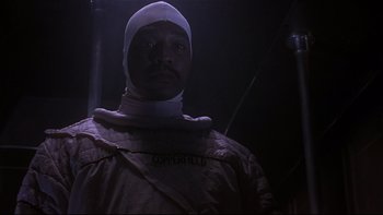 Movie still from “Phantoms” (1998), directed by Joe Chappelle – A man wearing a white bandage and a white hat; Close Up shot, Low angle