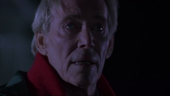 Movie still from “Phantoms” (1998), directed by Joe Chappelle – An old man with a red shirt and a black background; Close Up shot, Over the shoulder angle