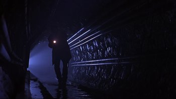 Movie still from “Phantoms” (1998), directed by Joe Chappelle – A man walking in the dark with a flashlight in his hand; Wide shot, Low angle