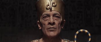 An old man wearing a gold crown and a gold robe