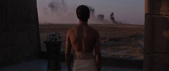 Movie still from “Pharaoh” (1966), directed by Jerzy Kawalerowicz – A man standing in front of an open field with smoke billowing from it; Wide shot, Over the shoulder angle