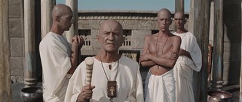 An old man holding a baseball bat in front of a group of men