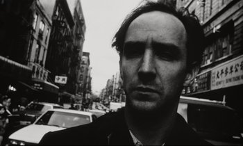 Movie still from “Pi” (1998), directed by Darren Aronofsky – Black and white photograph of a man in the street; Close Up shot, Low angle
