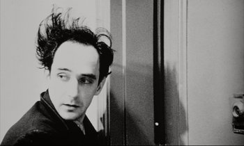 Movie still from “Pi” (1998), directed by Darren Aronofsky – A black and white photo of a man with a messy hair style; Close Up shot, Low angle
