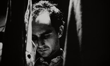 Movie still from “Pi” (1998), directed by Darren Aronofsky – Black and white photograph of a man looking down; Close Up shot, Low angle
