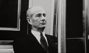 Movie still from “Pi” (1998), directed by Darren Aronofsky – An older man wearing a suit and tie looking out of a window; Close Up shot, Low angle