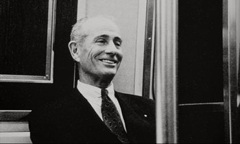 Movie still from “Pi” (1998), directed by Darren Aronofsky – An old black and white photo of a man smiling; Close Up shot, Low angle