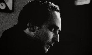 Movie still from “Pi” (1998), directed by Darren Aronofsky – Black and white photograph of a man's face in profile; Close Up shot, Low angle