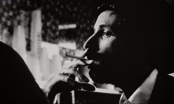 Movie still from “Pi” (1998), directed by Darren Aronofsky – A black and white photo of a man smoking a cigarette; Extreme Close Up shot, High angle