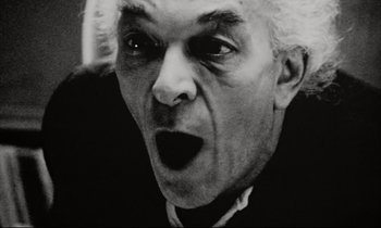 Movie still from “Pi” (1998), directed by Darren Aronofsky – An older man with a surprised look on his face; Close Up shot, Low angle