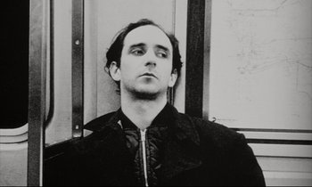 Movie still from “Pi” (1998), directed by Darren Aronofsky – Black and white photograph of a man in a black jacket; Close Up shot, Low angle