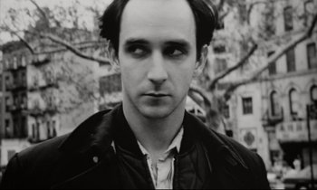 Movie still from “Pi” (1998), directed by Darren Aronofsky – Black and white photograph of a man in a black jacket; Close Up shot, High angle