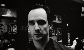 Movie still from “Pi” (1998), directed by Darren Aronofsky – Black and white photograph of a man in a black shirt; Close Up shot, Low angle