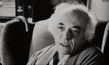 Movie still from “Pi” (1998), directed by Darren Aronofsky – An older man sitting in a chair looking at the camera; Close Up shot, Low angle