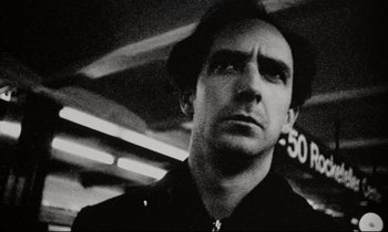 Movie still from “Pi” (1998), directed by Darren Aronofsky – Black and white photograph of a man looking at the camera; Close Up shot, Low angle