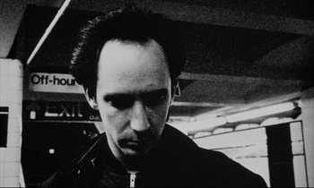 Movie still from “Pi” (1998), directed by Darren Aronofsky – A black and white photo of a man with a mohawk; Close Up shot, Low angle