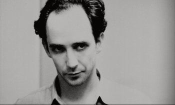 Movie still from “Pi” (1998), directed by Darren Aronofsky – Black and white photograph of a man looking at the camera; Close Up shot, Low angle