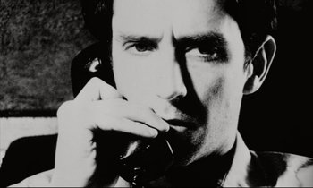 Movie still from “Pi” (1998), directed by Darren Aronofsky – Black and white photograph of a man on the phone; Extreme Close Up shot, Low angle