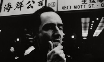 Movie still from “Pi” (1998), directed by Darren Aronofsky – Black and white photograph of a man in front of a building; Close Up shot, Low angle