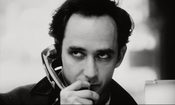 Movie still from “Pi” (1998), directed by Darren Aronofsky – A black and white photo of a man holding a cell phone to his ear; Close Up shot, Low angle