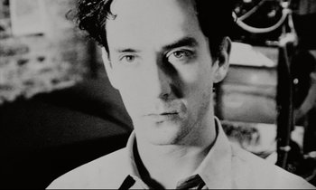 Movie still from “Pi” (1998), directed by Darren Aronofsky – Black and white photograph of a man in a shirt and tie; Close Up shot, Low angle