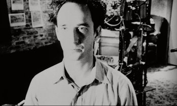 Movie still from “Pi” (1998), directed by Darren Aronofsky – Black and white photograph of a man in a room; Close Up shot, Low angle