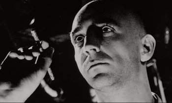 Movie still from “Pi” (1998), directed by Darren Aronofsky – A black - and - white photo of a man looking up; Extreme Close Up shot, Low angle