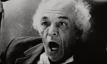 Movie still from “Pi” (1998), directed by Darren Aronofsky – An older man with a surprised look on his face; Close Up shot, Low angle
