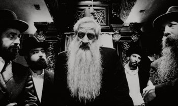 Movie still from “Pi” (1998), directed by Darren Aronofsky – A man with a long white beard standing next to two other men; Close Up shot, Low angle