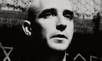 Movie still from “Pi” (1998), directed by Darren Aronofsky – A black and white photo of a man with a bald head; Close Up shot, Low angle