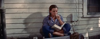 Movie still from “Picnic” (1955), directed by Joshua Logan – A woman sitting on the ground reading a book; Medium shot, High angle