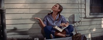 Movie still from “Picnic” (1955), directed by Joshua Logan – A woman sitting on the ground holding a book; Medium shot, Low angle
