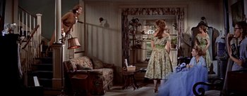Movie still from “Picnic” (1955), directed by Joshua Logan – A woman in a floral dress in front of a living room; Wide shot, Low angle